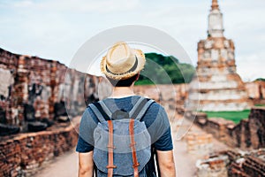 Back of Asian male solo traveller walks inside historical buddhist ruins heritage