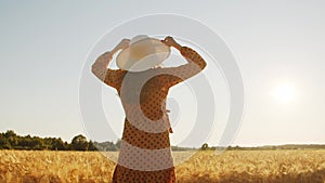 Back of a beautiful young pregnant woman in the rays of the sunset. Girl in the countryside field. Freedom and happiness