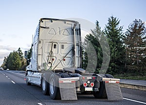 Back of big rig semi truck tractor with high cab for long haul freights running on the highway road to warehouse for pick up