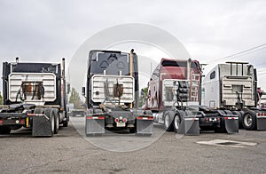 Back of big rigs semi trucks standing in row on truck stop parking lot