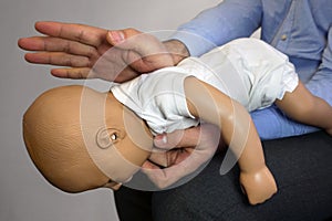 Back blows the Heimlich maneuver or Heimlich manoeuvre on a simulation mannequin infant dummy during medical training Basic Life photo