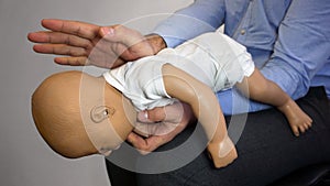 Back blows the Heimlich maneuver or Heimlich manoeuvre on a simulation mannequin infant dummy during medical training Basic Life photo