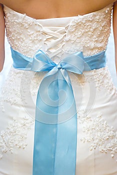 Back of bride in white lace wedding dress with blue ribbon