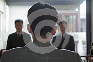 Back of Businessman's Head, Two Businessman Coming Towards Him