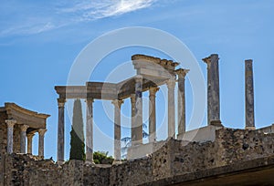 Back of the capitals and columns of the Roman theater of Merida, with the midday sun illuminating the columns and the ruins of