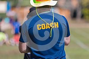 Back of a coach`s blue color shirt with the word Coach in yellow