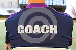 Back of a coach`s dark blue color shirt with the word Coach writ