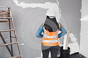 The back of a construction worker in uniform as she faces work in progress