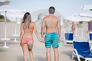 Back couple walking on the beach. On the back of a man and on the woman`s buttocks is handprint of sand