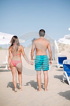 Back couple walking on the beach. On the back of a man and on the woman`s buttocks is handprint of sand