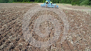 Back of cultivator tractor with discs cultivating stubble field soil in farmland
