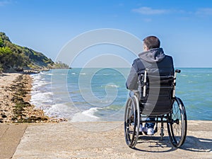 Back of disabled man in wheelchair at beach