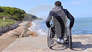 Back of disabled man in wheelchair at beach slow motion