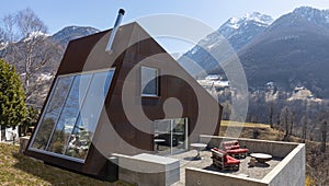 Back exterior of modern isolated villa with garden, surrounded by nature. Beautiful landscape of Swiss Alps