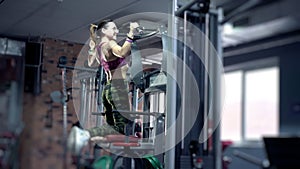 Back of fit 30s woman performing pull ups in gym. Good looking mature woman lives an active lifestyle maintaining her