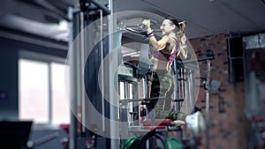 Back of fit 30s woman performing pull ups in gym. Good looking mature woman lives an active lifestyle maintaining her