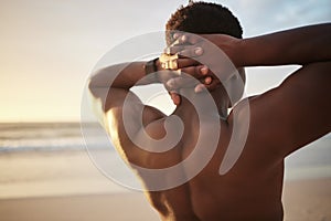 Back of a fit muscle man with hands behind his head, at the beach looking at the view during sunset. Rear view of a