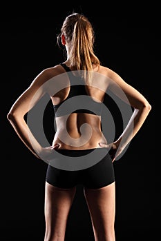 Back of fit young woman in black sports outfit