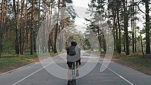 Back follow shot of fit sportive cyclist in black outfit riding bicycle. Legs with strong muscles pedaling bicycle. Cycling concep