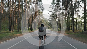 Back follow shot of fit sportive cyclist in black outfit riding bicycle. Legs with strong muscles pedaling bicycle Cycling concept