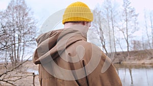 Back frame of a young traveller with yellow backpack walking in the forest.