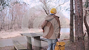 Back frame of a young traveller with yellow backpack walking in the forest.