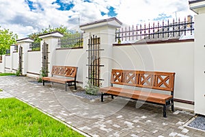 Back and front yard cottage garden, flowering plant and green grass lawn, brown pavement and orange brick wall, evergreen trees on