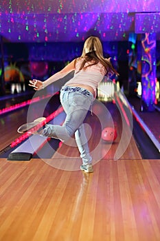 Back of girl making throw of ball in bowling club