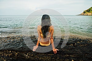 Back girl in yellow bikini on stony shore blue sea. girl in yellow bikini