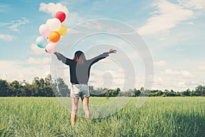 Back of happy young woman standing on green field enjoy with fresh air.