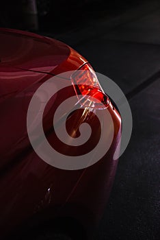 Back headlight of a modern luxury red car, auto detail, car care concept in the garage