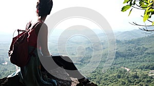 Back lit of one young woman sitting on rock and watching view background on sunny day