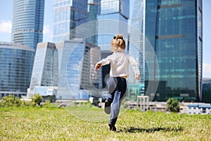 Back of little girl running on grass near