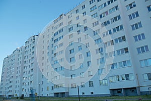 The back of a long nine-story apartment building with a white facade, with rows of Windows and loggias, going into perspective. photo