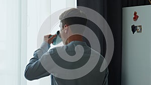 Back man drinking coffee looking window at morning. Guy thinking about success.