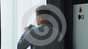 Back man drinking coffee looking window at morning. Guy thinking about success.