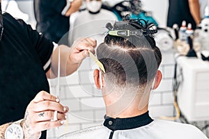 Back of a man sitting in a hairdressing salon while having his hair cut