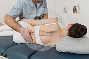 Back massage. Chiropractor or osteopath fixing back during visit in manual therapy clinic. Doctor doing shoulder blade