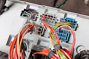 The back of the metal casing of the device with white, black and blue connectors with connected multi-colored electrical wires for