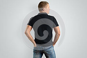 Back Mockup black cotton polo shirt on a man posing on a gray