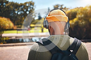 Back, music headphones and student outdoor, listening to audio or streaming sound online. Radio, podcast and man at park