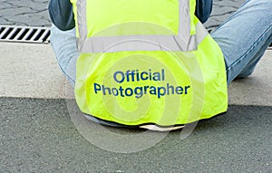 The back of an official photographer sitting, photographing an event
