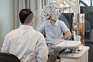 Back of optical staff prepare and use machine for processing of eyecare for children in optical shop