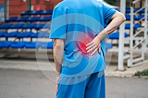 Back pain, kidney inflammation, man suffering from backache on a sports ground after workout