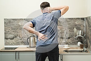 Back pain, man with backache at home on pink background