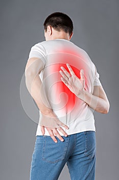 Back pain, man suffering from backache on gray background