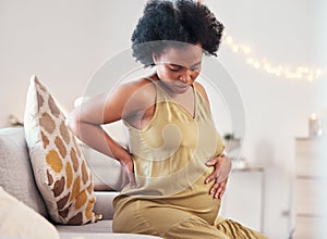 Back pain, stomach and pregnant woman with healthcare stress, problem or risk on sofa in her living room. Backache