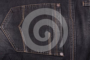 Back pocket of dark jeans close up