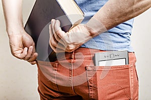 In the back pocket of jeans is an e-book, a man tries to shove in a second pocket paper book