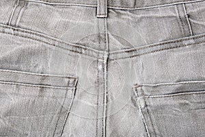 Back pocket of used grey jeans, grunge clothes close up